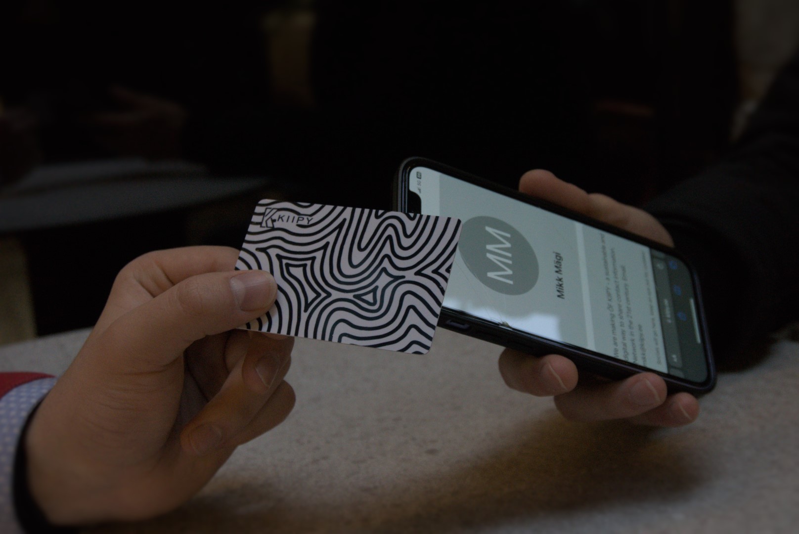 A person using a KIIPY card to share contact info.